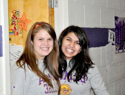 Two female roommates smile outside of their dorm room in Columbia Hall